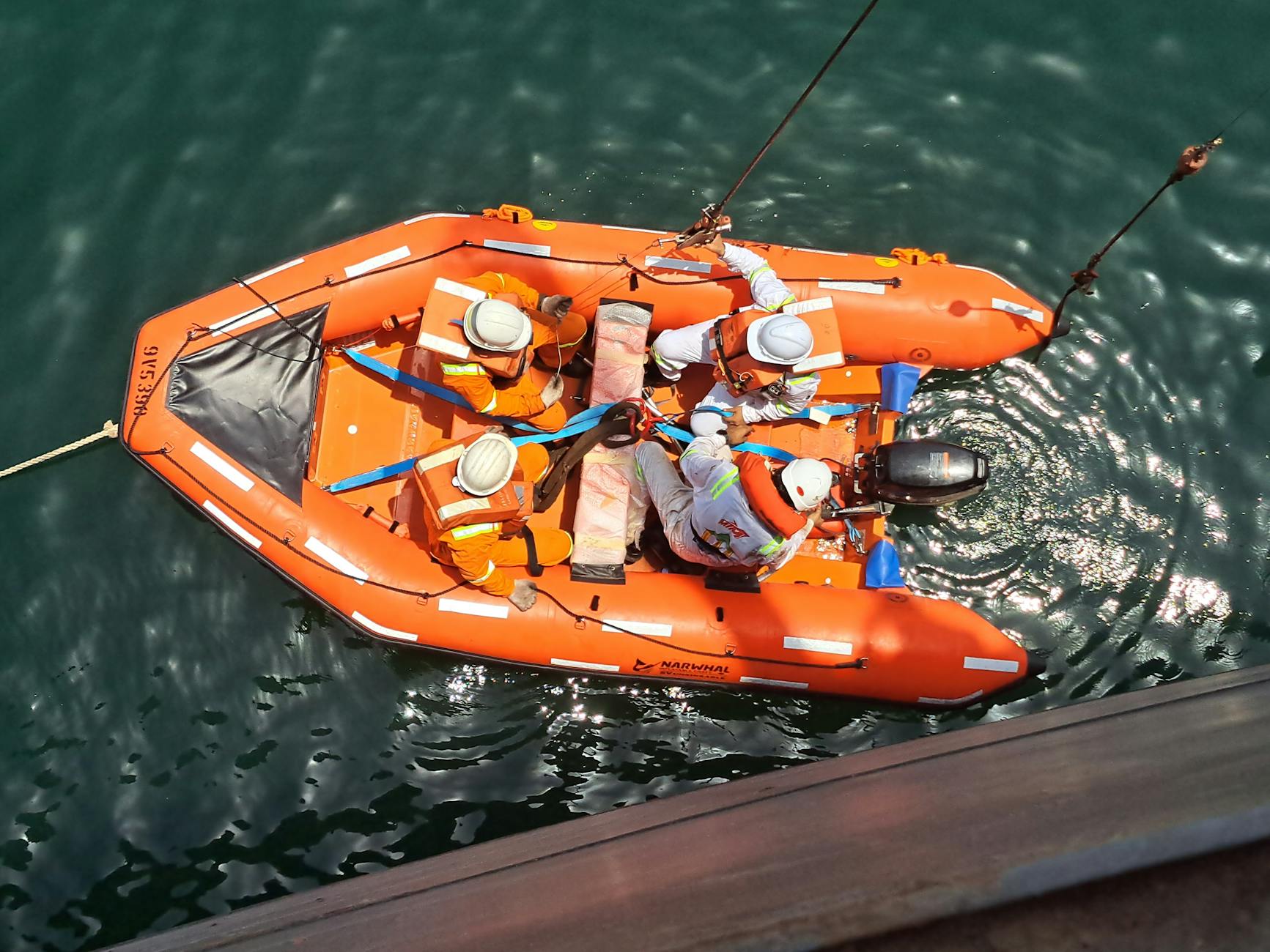 Grupa osób w łodzi ratunkowej ćwiczy akcję na otwartej wodzie