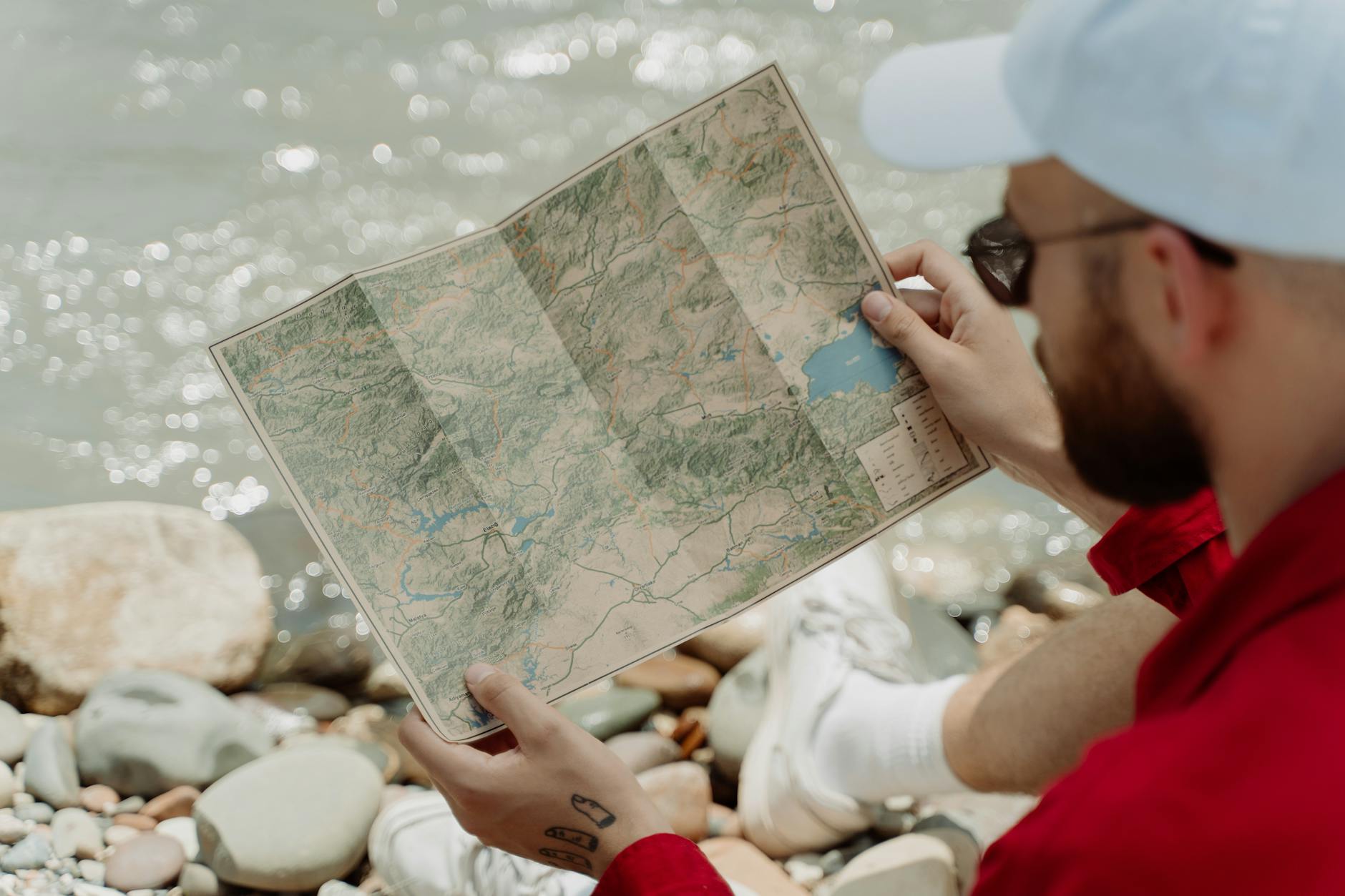 Mężczyzna nad skalistą rzeką analizuje mapę trasy kajakowej