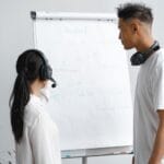 Dwóch pracowników call center w słuchawkach omawia projekt